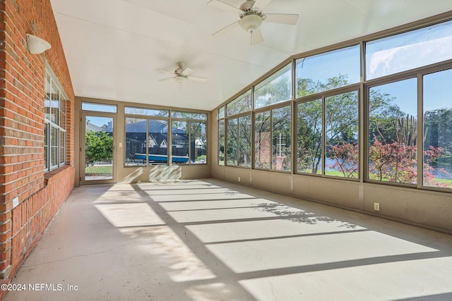 unfurnished sunroom featuring lofted ceiling, a healthy amount of sunlight, and ceiling fan