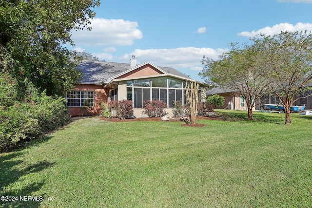 rear view of house with a sunroom and a lawn