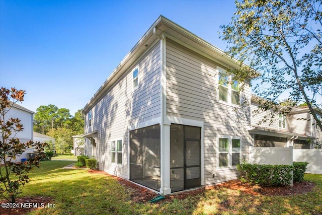 rear view of house with a lawn and a sunroom