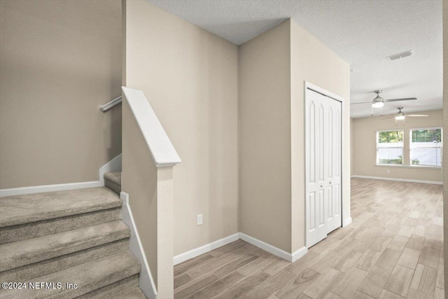 staircase featuring a textured ceiling, wood-type flooring, and ceiling fan