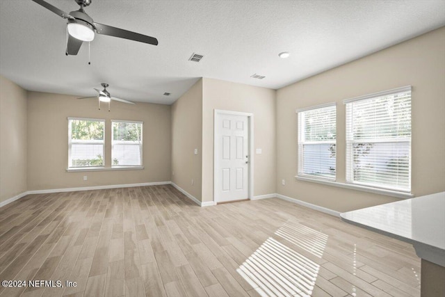 unfurnished living room with light hardwood / wood-style floors, a textured ceiling, and ceiling fan