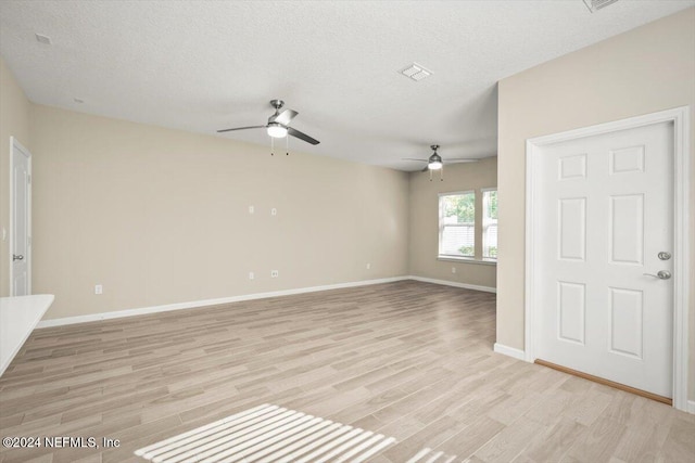 empty room featuring a textured ceiling, light hardwood / wood-style floors, and ceiling fan