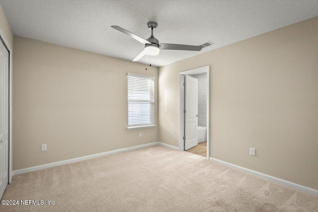 unfurnished bedroom with light carpet, a textured ceiling, a closet, and ceiling fan