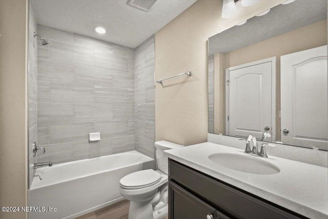 full bathroom featuring tiled shower / bath, hardwood / wood-style floors, a textured ceiling, toilet, and vanity