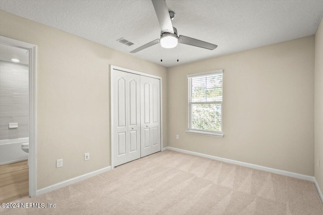 unfurnished bedroom featuring light carpet, a closet, and ceiling fan