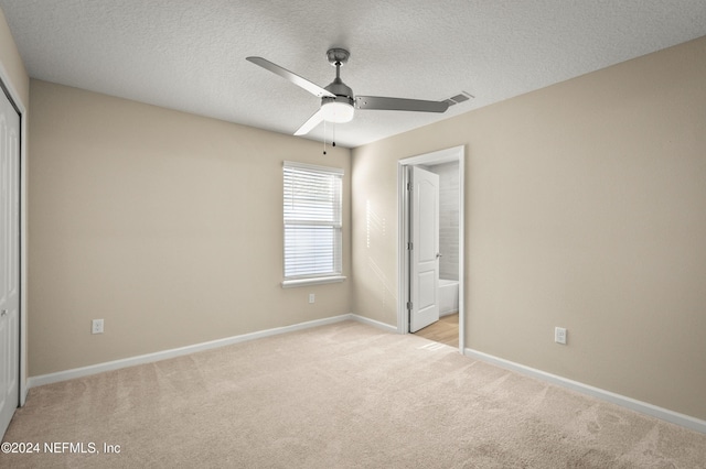 unfurnished bedroom featuring a textured ceiling, light colored carpet, a closet, and ceiling fan