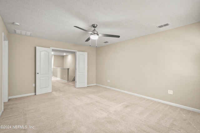 unfurnished bedroom with ceiling fan, light carpet, and a textured ceiling