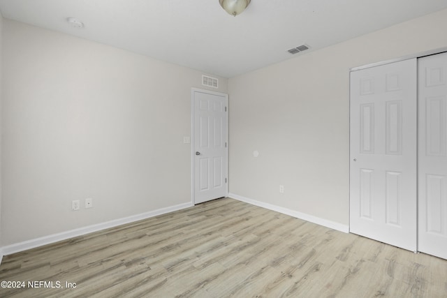 unfurnished bedroom with a closet and light wood-type flooring