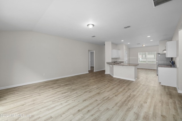 unfurnished living room featuring sink, vaulted ceiling, and light wood-type flooring