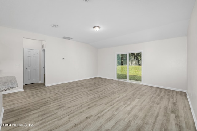 spare room with light hardwood / wood-style flooring and lofted ceiling