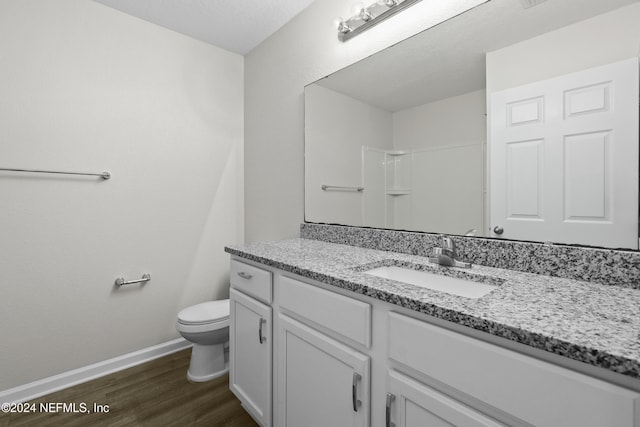 bathroom featuring vanity, toilet, walk in shower, and hardwood / wood-style floors