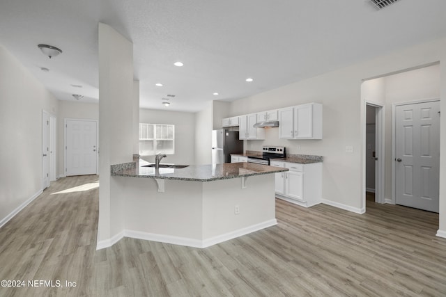 kitchen featuring light wood-type flooring, a kitchen breakfast bar, stainless steel appliances, white cabinets, and dark stone countertops