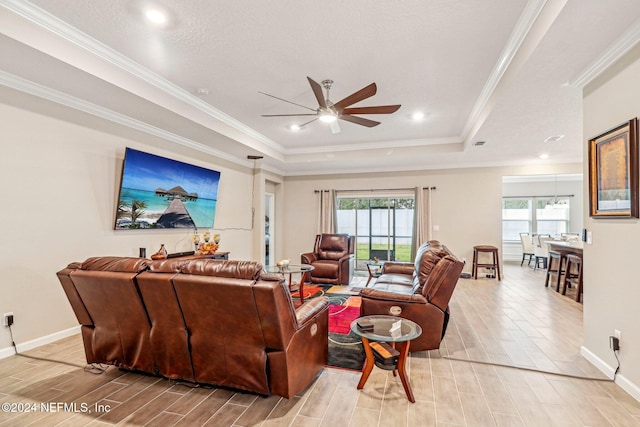 living room featuring a wealth of natural light, crown molding, a tray ceiling, and light hardwood / wood-style floors