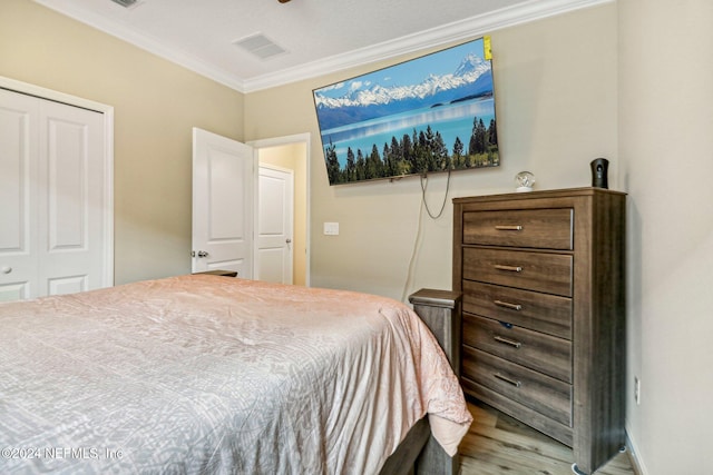 bedroom with a closet, ornamental molding, and hardwood / wood-style flooring