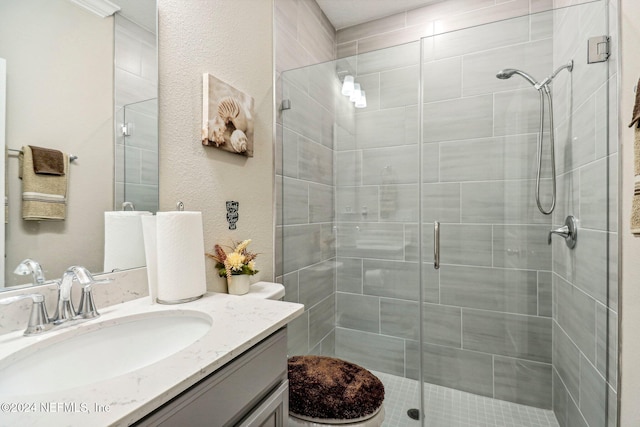 bathroom featuring vanity, toilet, and a shower with door