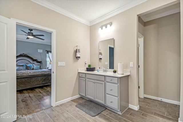 bathroom featuring ceiling fan, a textured ceiling, hardwood / wood-style flooring, ornamental molding, and vanity