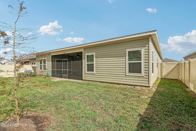 back of house with a sunroom and a lawn