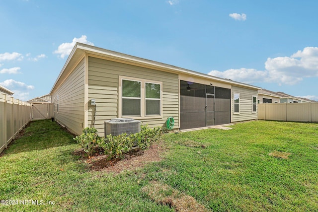 rear view of house with a yard, central air condition unit, and a sunroom