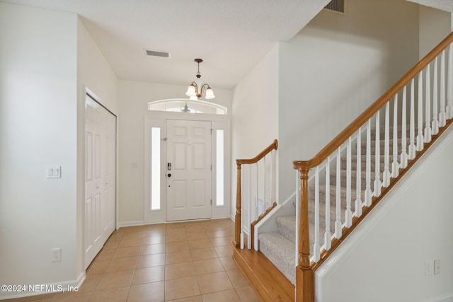 tiled entryway featuring a notable chandelier