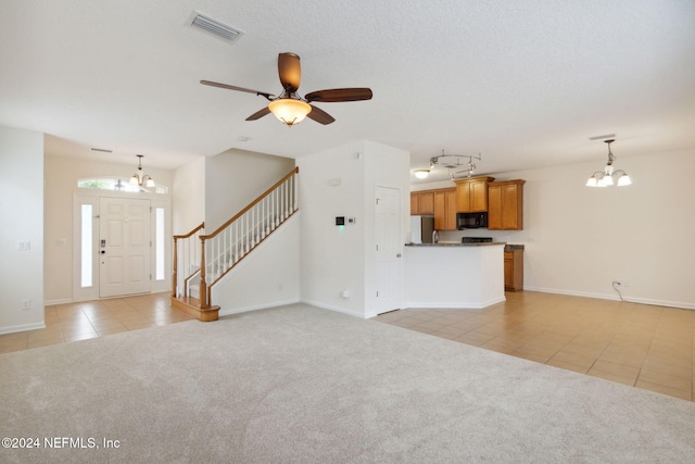 unfurnished living room featuring a textured ceiling, light colored carpet, and ceiling fan with notable chandelier