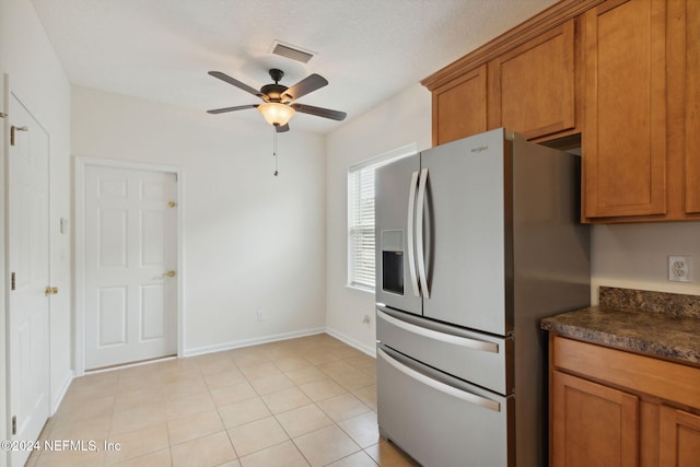 kitchen featuring ceiling fan, a textured ceiling, stainless steel fridge with ice dispenser, and light tile patterned floors