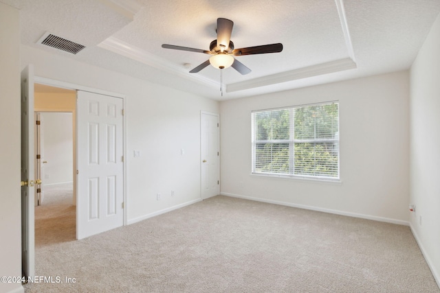 carpeted empty room with ornamental molding, a textured ceiling, a tray ceiling, and ceiling fan