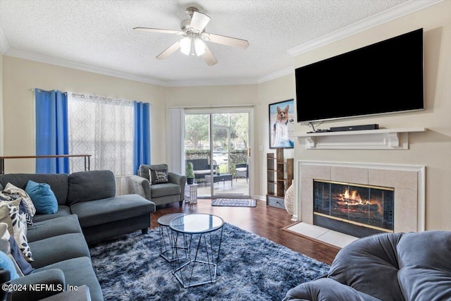 living room with ornamental molding, a textured ceiling, a fireplace, and hardwood / wood-style floors