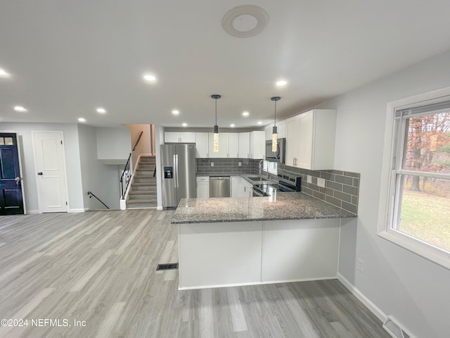 kitchen featuring stainless steel appliances, white cabinets, kitchen peninsula, decorative backsplash, and pendant lighting