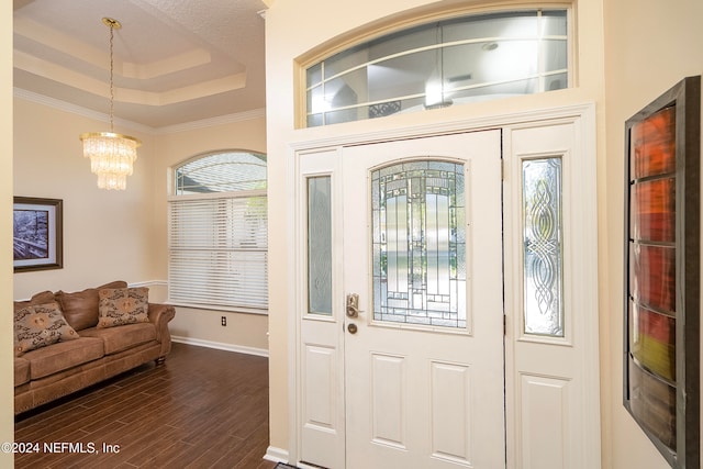 entryway featuring ornamental molding, an inviting chandelier, dark hardwood / wood-style floors, and a tray ceiling