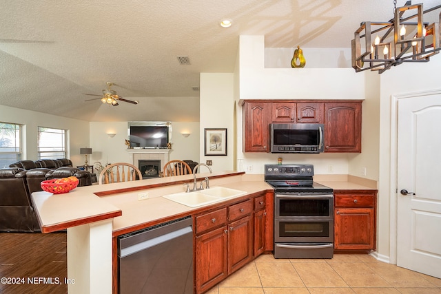 kitchen with kitchen peninsula, sink, light tile patterned floors, appliances with stainless steel finishes, and a textured ceiling