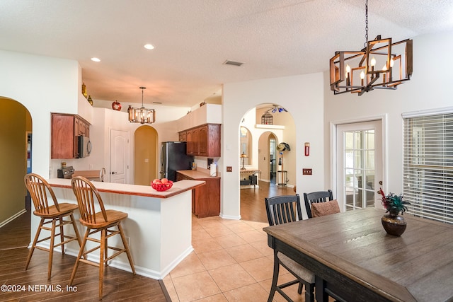 kitchen featuring light hardwood / wood-style flooring, appliances with stainless steel finishes, a textured ceiling, kitchen peninsula, and a breakfast bar