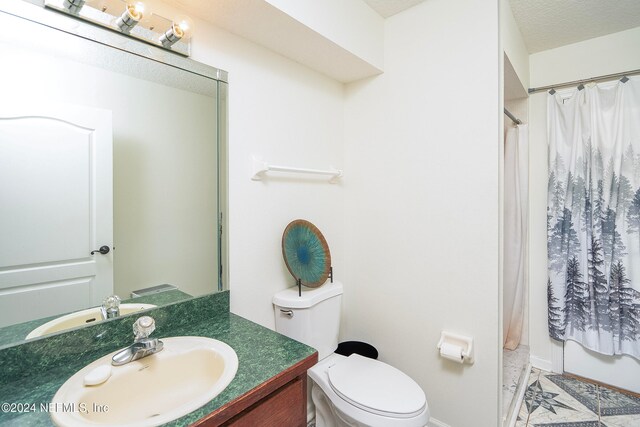 bathroom with toilet, a textured ceiling, curtained shower, and vanity