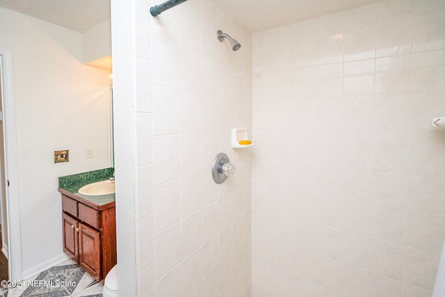 bathroom featuring vanity, a textured ceiling, toilet, and tiled shower