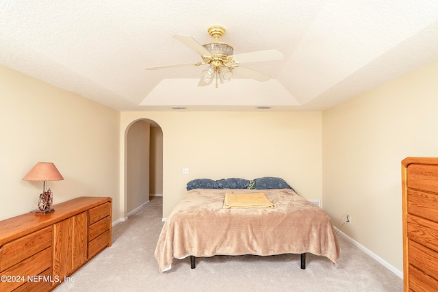 carpeted bedroom featuring a textured ceiling, a tray ceiling, and ceiling fan