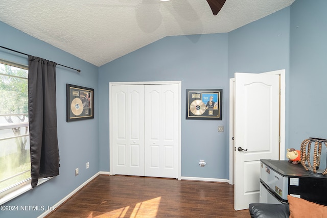 bedroom with lofted ceiling, dark hardwood / wood-style flooring, ceiling fan, a textured ceiling, and a closet