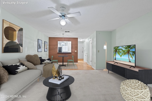 carpeted living area with visible vents, ceiling fan, and a textured ceiling