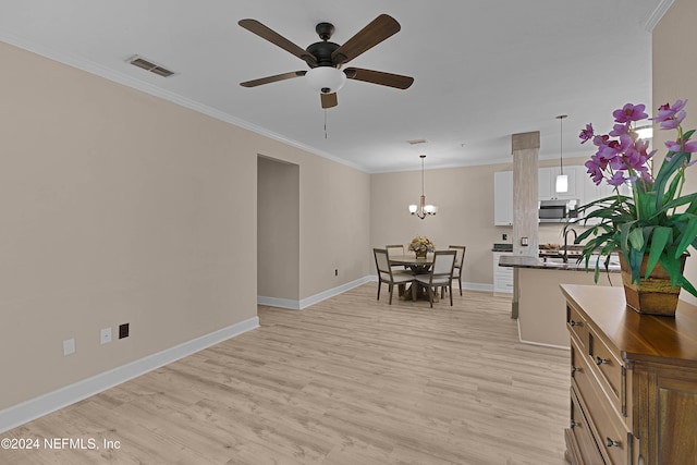 interior space featuring light hardwood / wood-style flooring, ornamental molding, and ceiling fan with notable chandelier