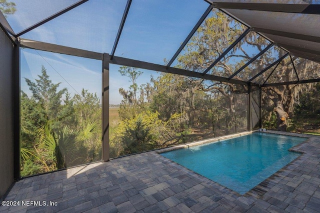 view of swimming pool featuring a patio and a lanai