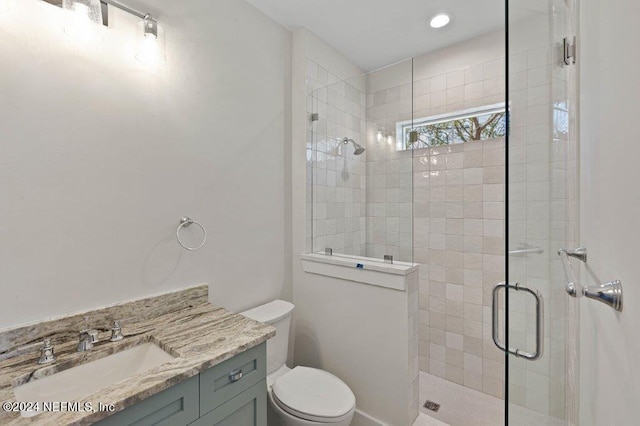 bathroom featuring vanity, a shower with shower door, and toilet