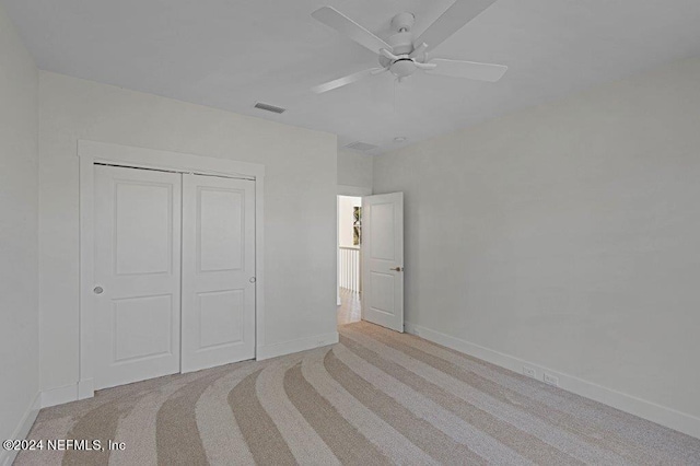 unfurnished bedroom featuring light carpet, a closet, and ceiling fan