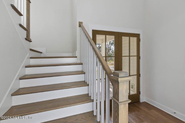 stairs with french doors and hardwood / wood-style floors