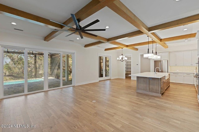 unfurnished living room featuring beam ceiling, ceiling fan with notable chandelier, and light wood-type flooring