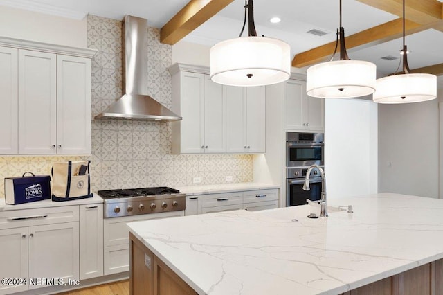 kitchen featuring light stone counters, hanging light fixtures, stainless steel appliances, wall chimney exhaust hood, and beam ceiling