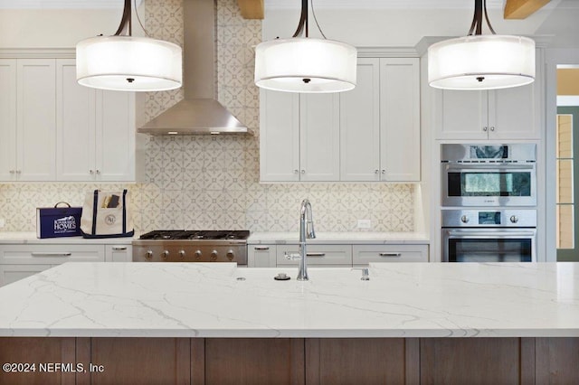 kitchen with wall chimney exhaust hood, white cabinets, and pendant lighting