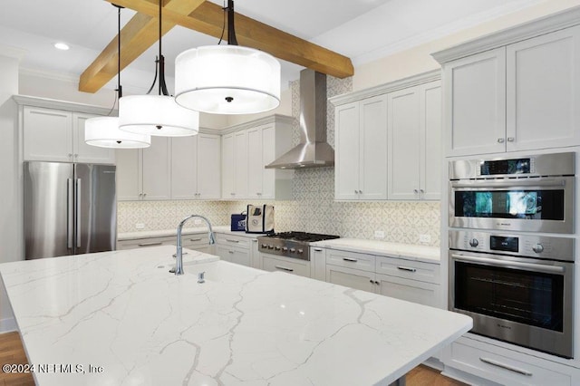 kitchen featuring stainless steel appliances, wall chimney exhaust hood, beamed ceiling, and decorative light fixtures