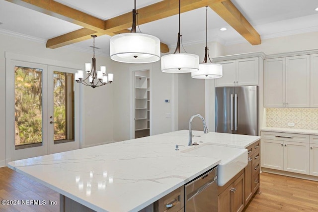 kitchen featuring appliances with stainless steel finishes, light wood-type flooring, an island with sink, white cabinetry, and decorative light fixtures