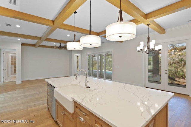 kitchen with a center island with sink, stainless steel dishwasher, hanging light fixtures, and light hardwood / wood-style floors