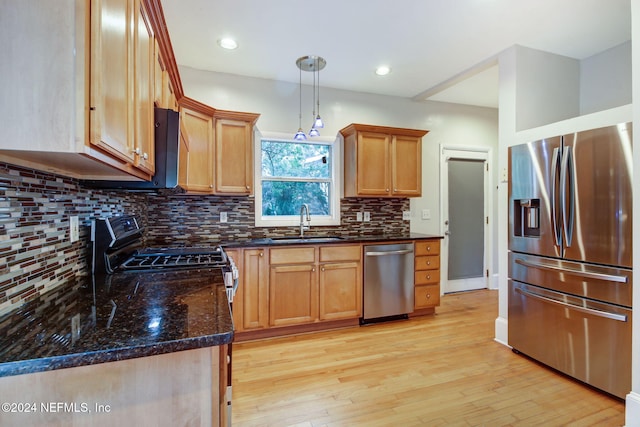 kitchen featuring decorative light fixtures, tasteful backsplash, sink, light hardwood / wood-style floors, and stainless steel appliances