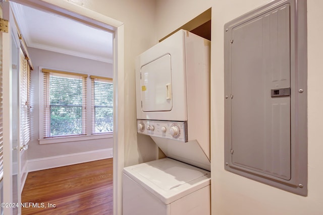 clothes washing area with crown molding, stacked washer and dryer, electric panel, and hardwood / wood-style floors