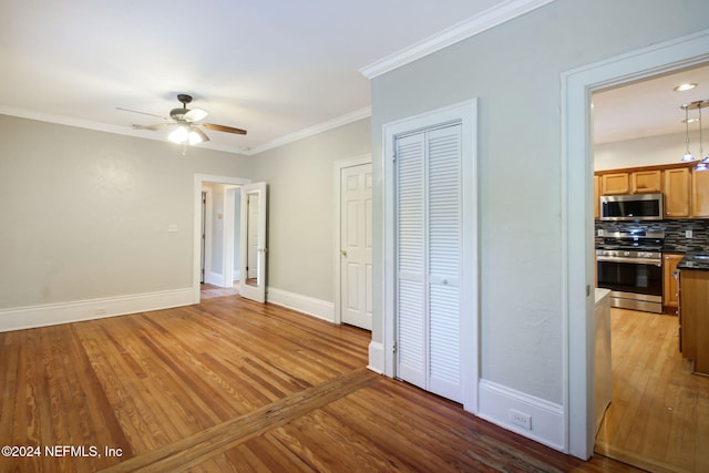 unfurnished bedroom featuring ornamental molding, wood-type flooring, and ceiling fan